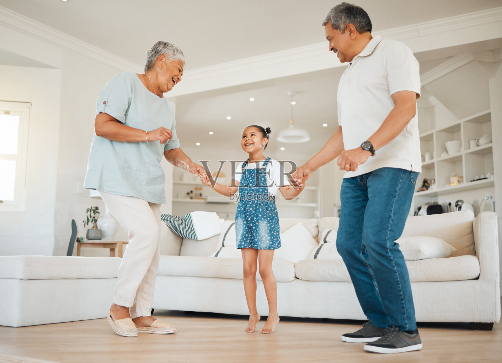 一个可爱的小女孩和她的祖父母在客厅跳舞照片摄影图片