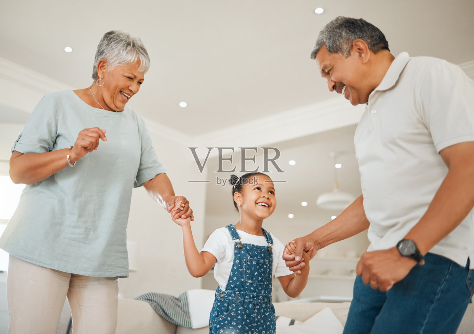 一个可爱的小女孩和她的祖父母在客厅跳舞照片摄影图片