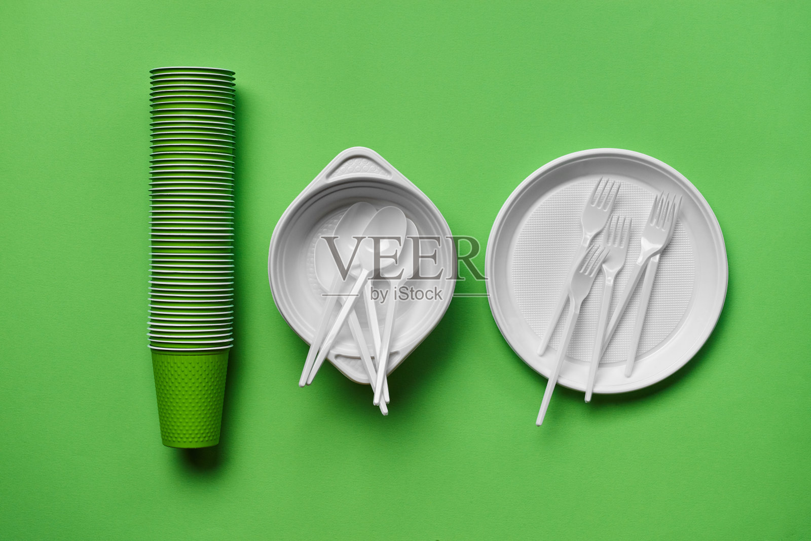 彩色塑料一次性餐具在绿色背景与复制空间。野餐用具的概念。前视图。有选择性的重点。特写镜头照片摄影图片