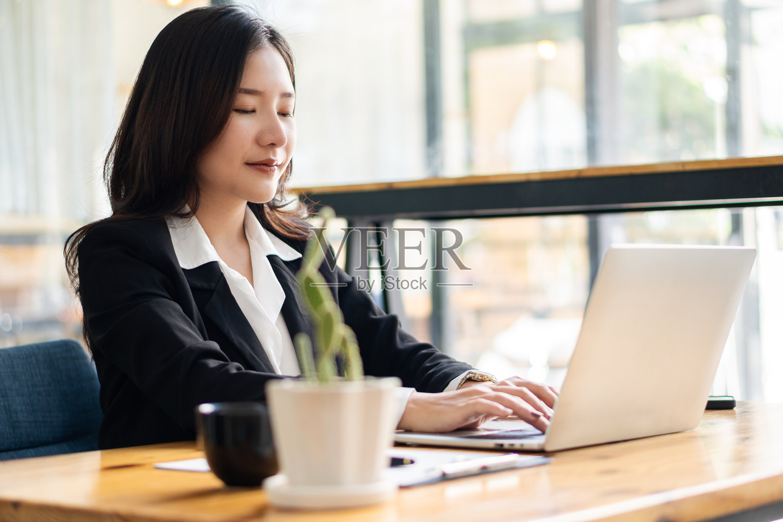 工作概念亚洲女商人使用笔记本电脑在咖啡店与顾客进行网络交流在饮食店坐在笔记本电脑和智能手机上的美女照片摄影图片