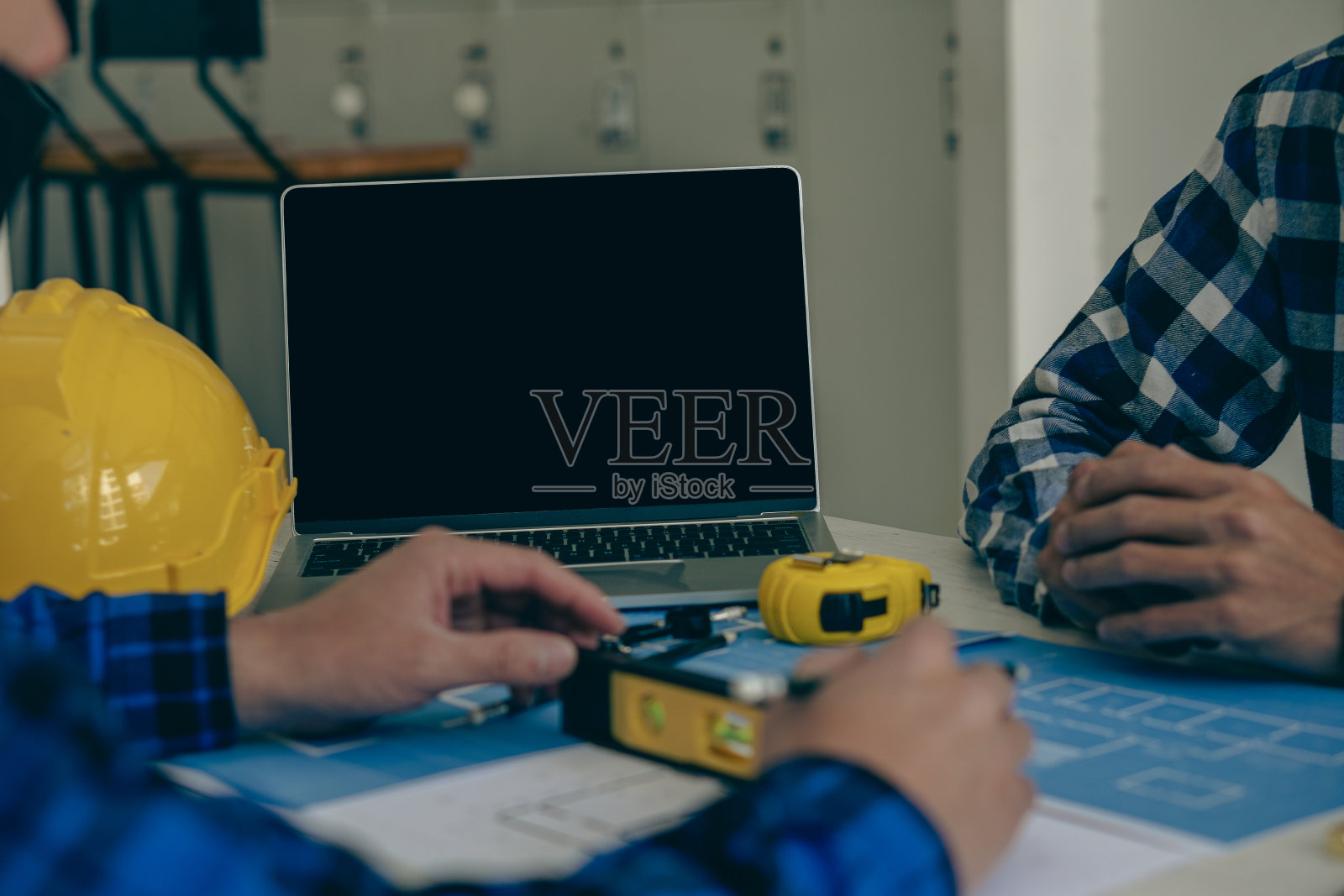 现场工程对象与互动伙伴一起工作，并在幕后指指蓝图，使用笔记本电脑绘制办公楼设计项目。照片摄影图片