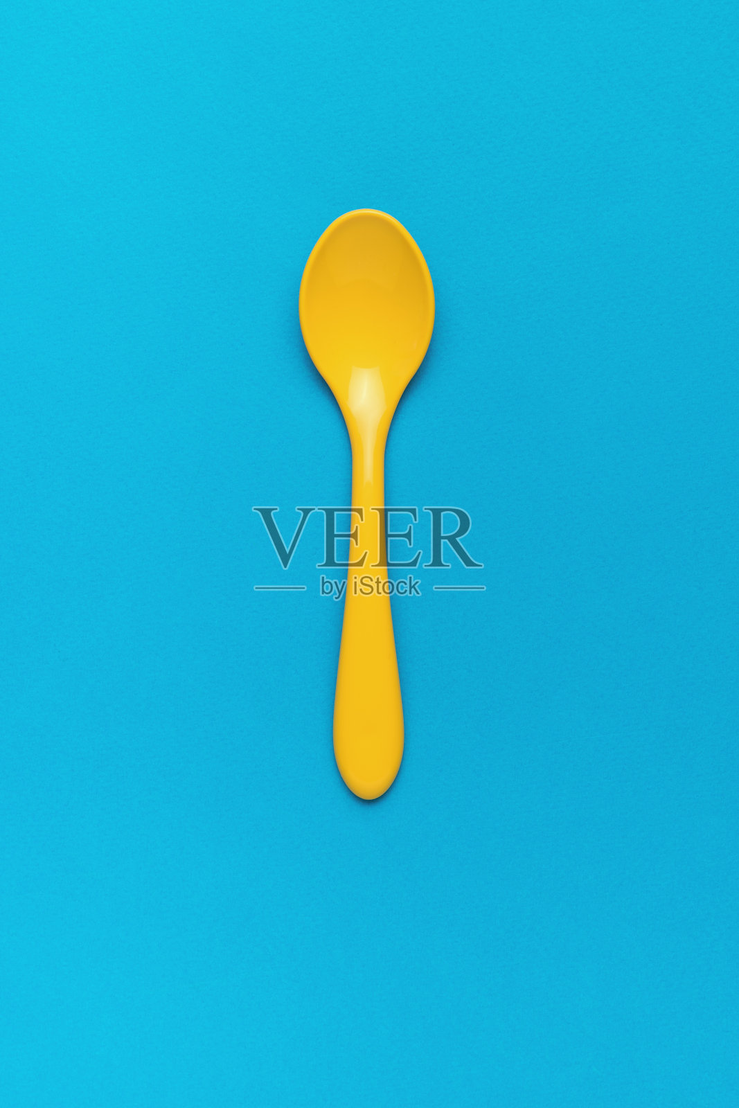 蓝色背景的儿童塑料勺。平的。照片摄影图片