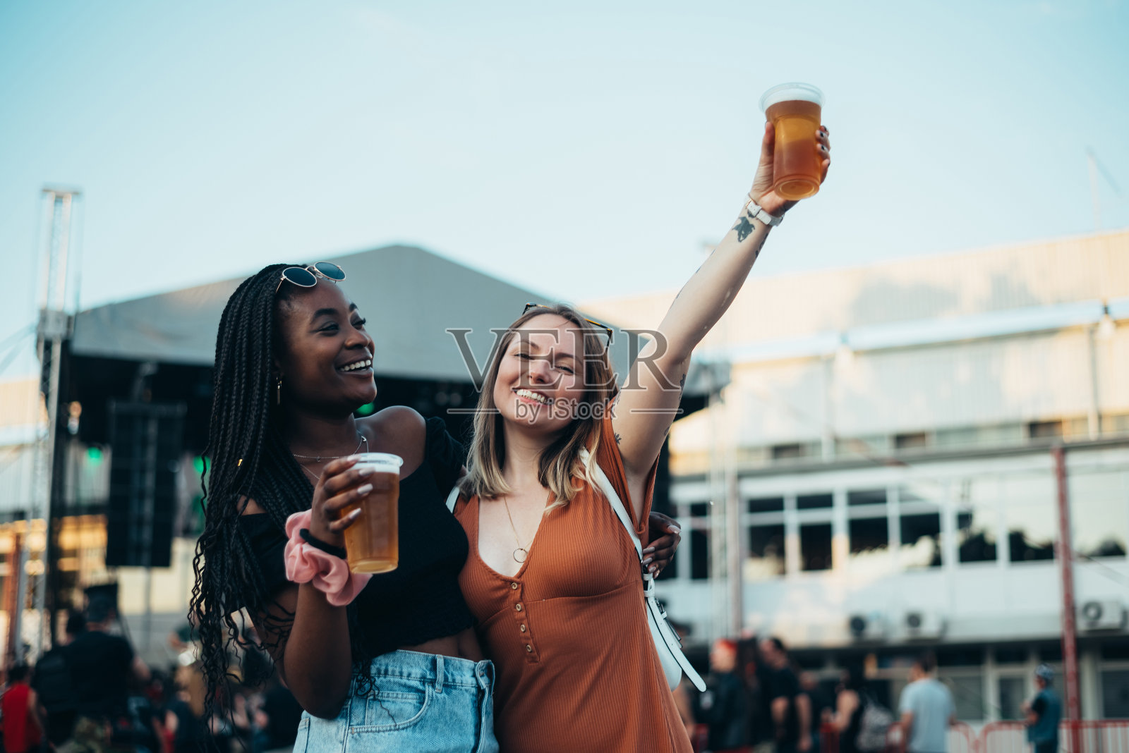 两个美丽的朋友在音乐节上喝啤酒，玩得很开心照片摄影图片