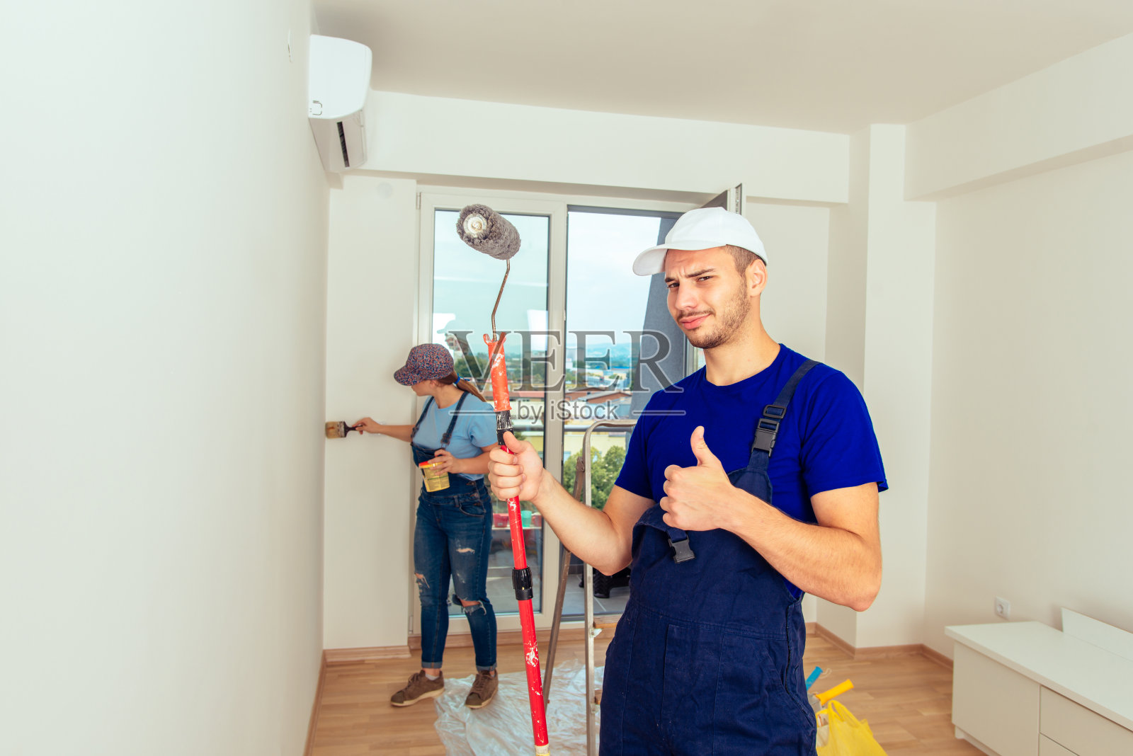 一对年轻夫妇在家里刷墙照片摄影图片