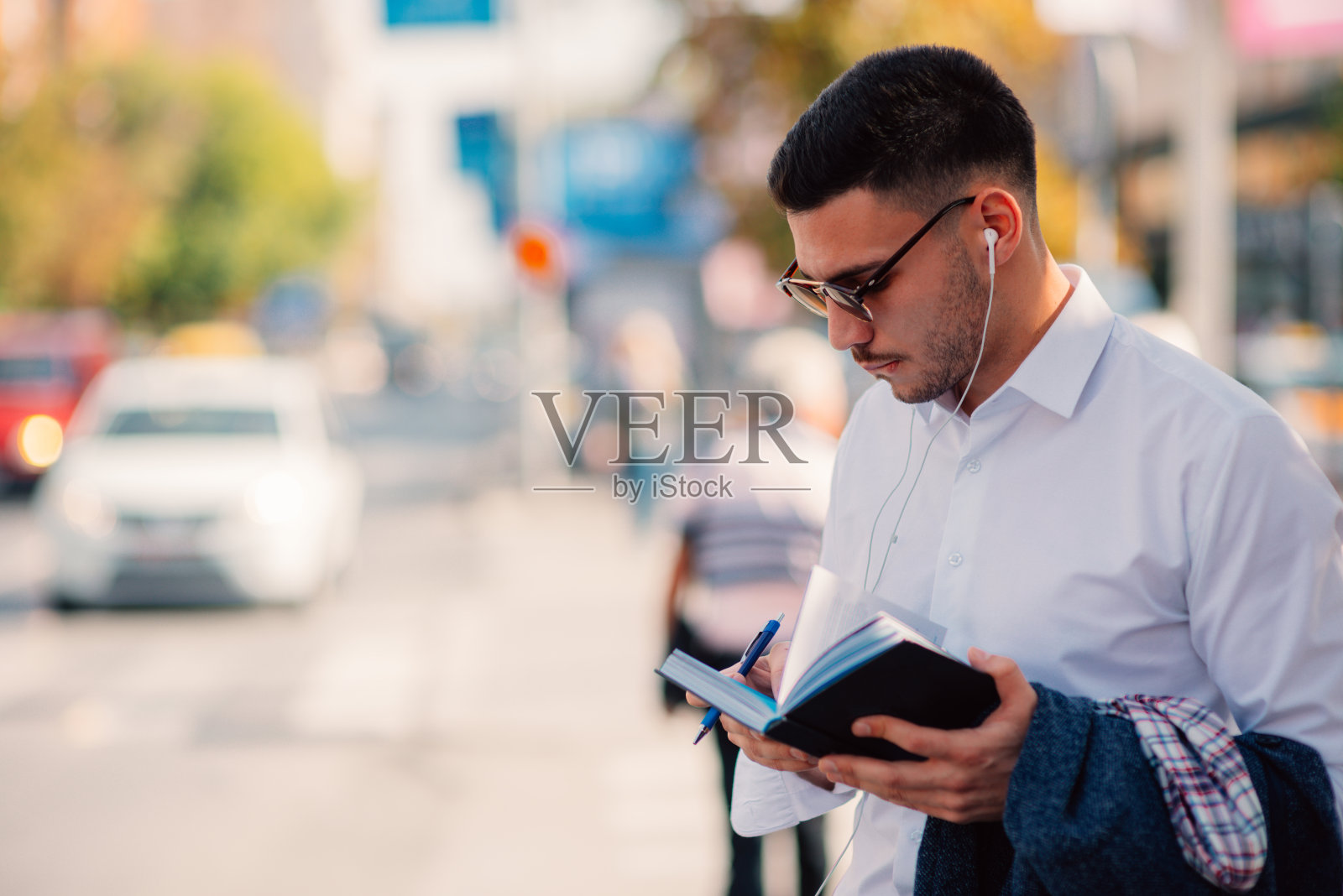 一位穿着白衬衫的现代年轻商人正严肃地站在城市里看书。照片摄影图片