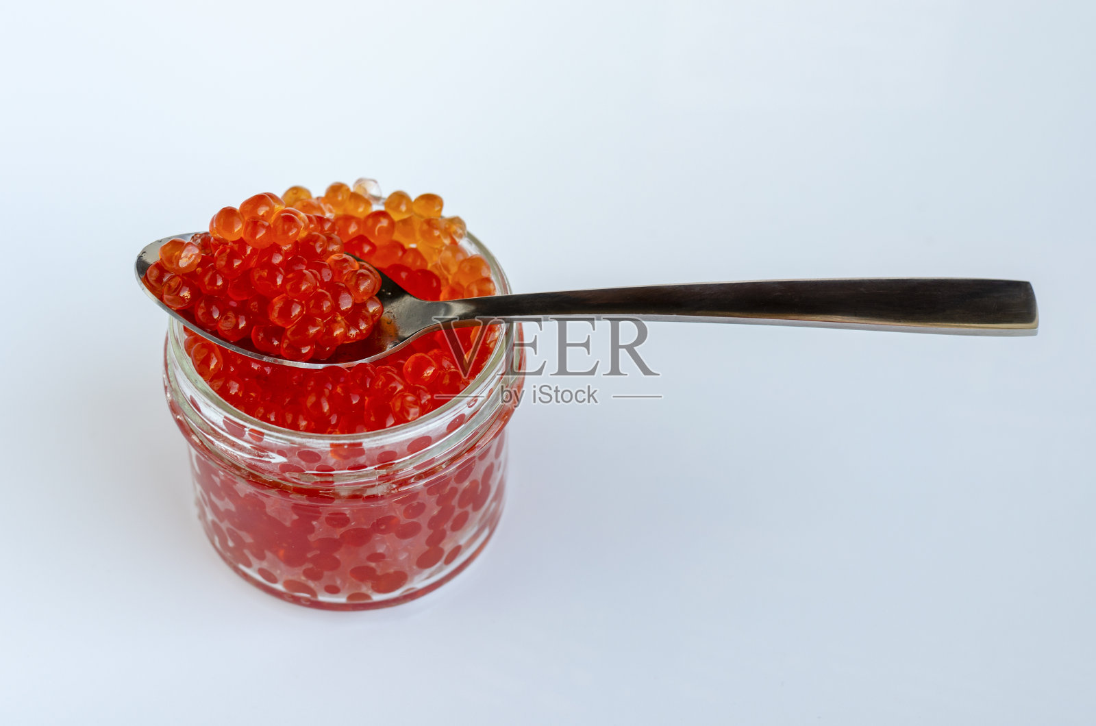 红鱼子酱。红色鱼子酱勺装在玻璃碗里。生海鲜。豪华精致的食物。照片摄影图片