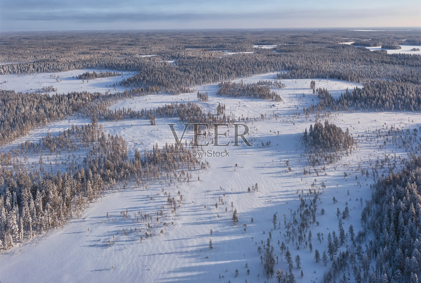 鸟瞰芬兰拉普兰的冬季景观。日落时白雪覆盖的冷杉树照片摄影图片