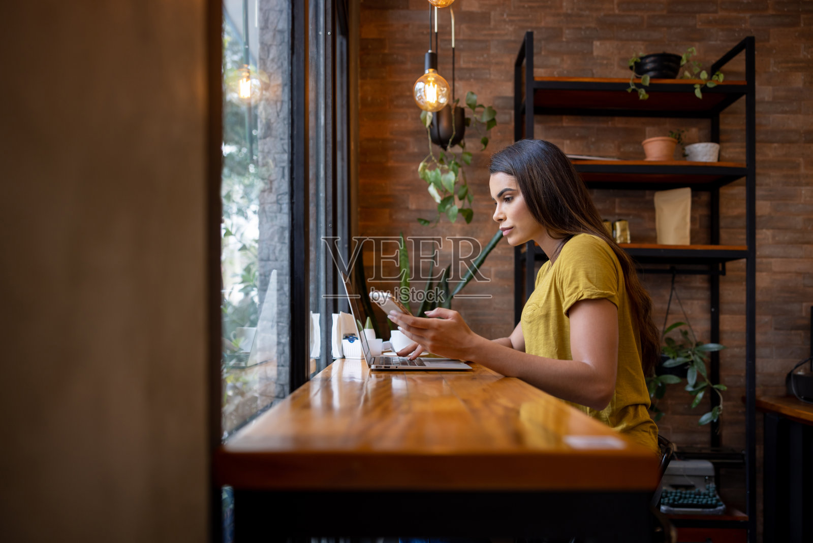 在咖啡馆用手提电脑和手机工作的忙碌女人照片摄影图片