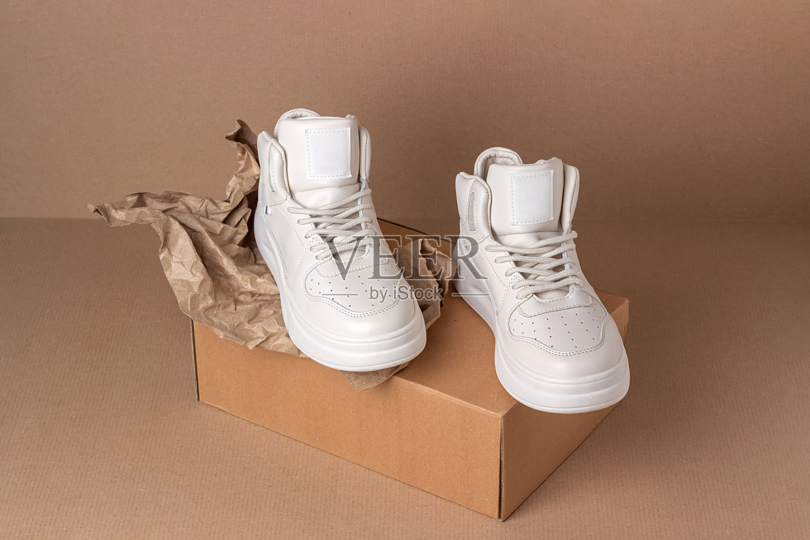 Eco皮鞋。一双棕色背景的米色运动鞋。最小的风格。休闲运动生活理念照片摄影图片