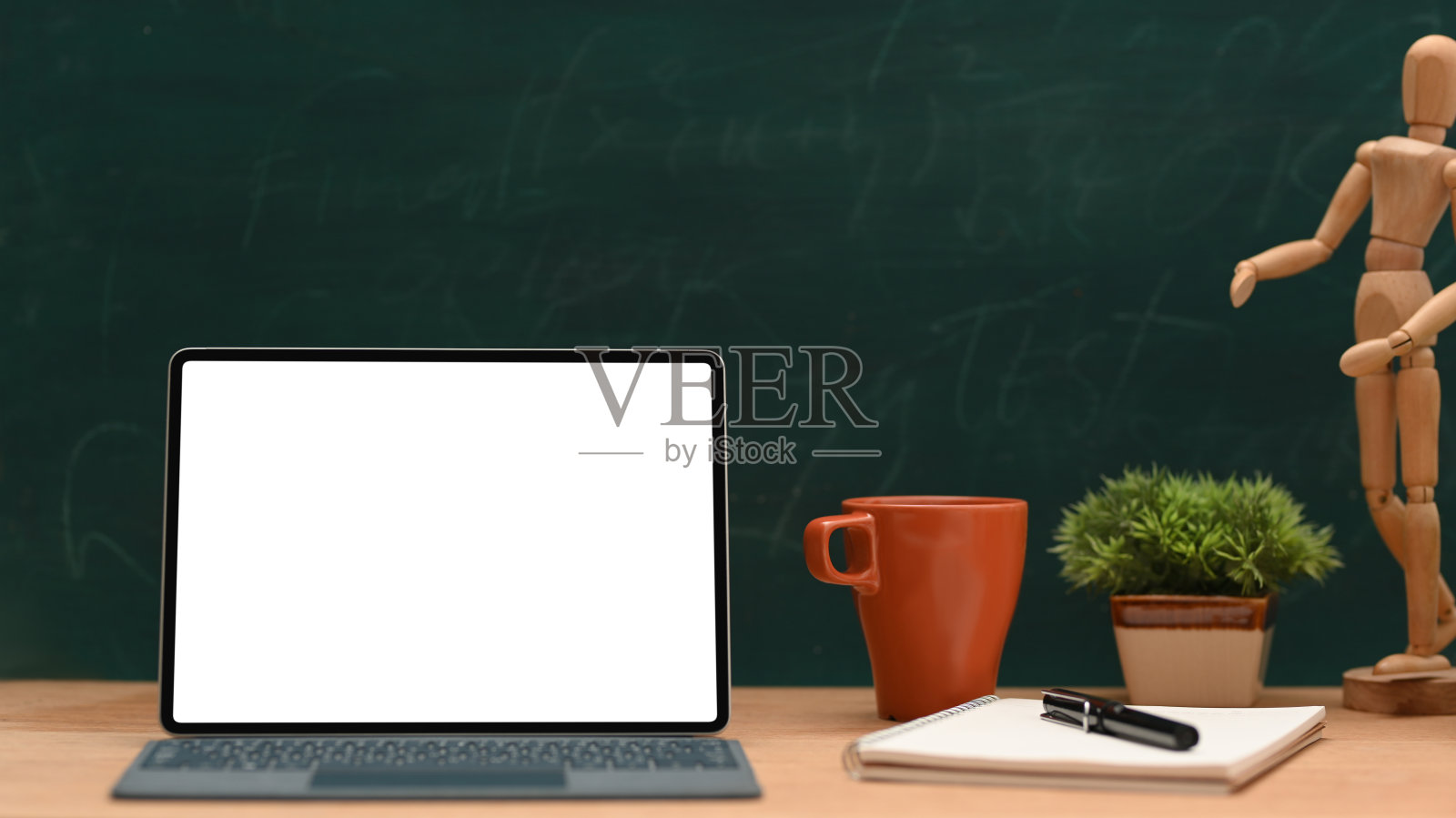 在绿色黑板背景的木制桌子上的笔记本电脑模型照片摄影图片