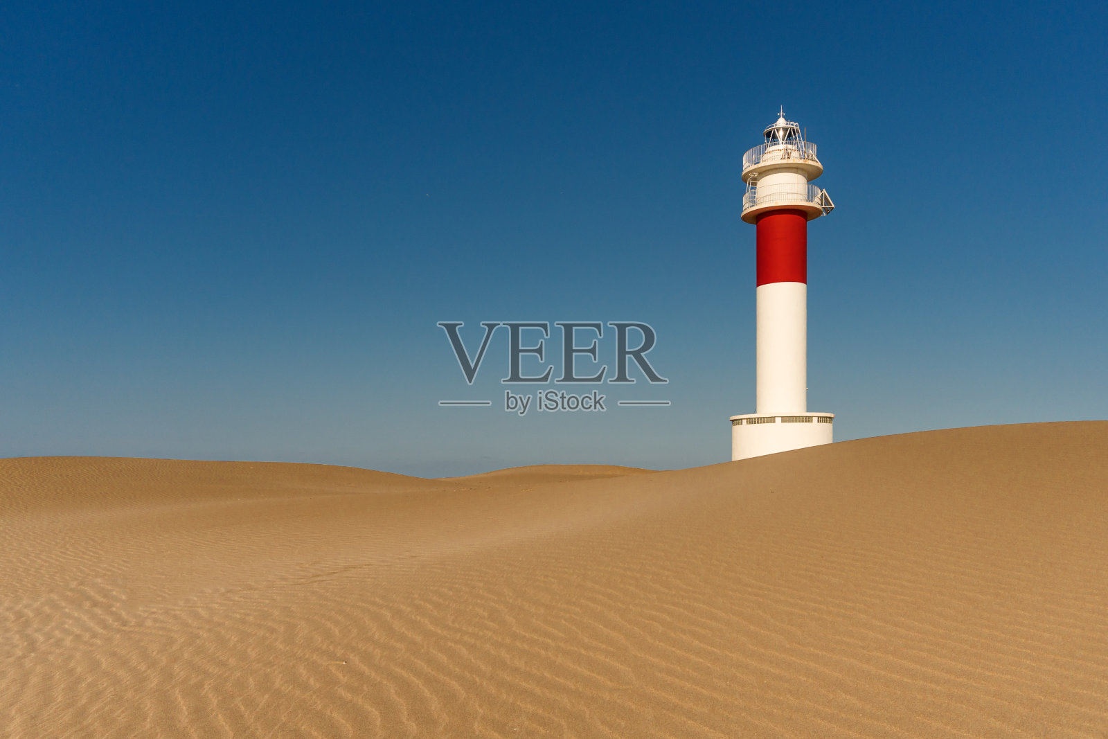 在一个阳光明媚的日子里，位于范加尔海滩沙丘之间的德尔塔德尔埃布罗灯塔照片摄影图片