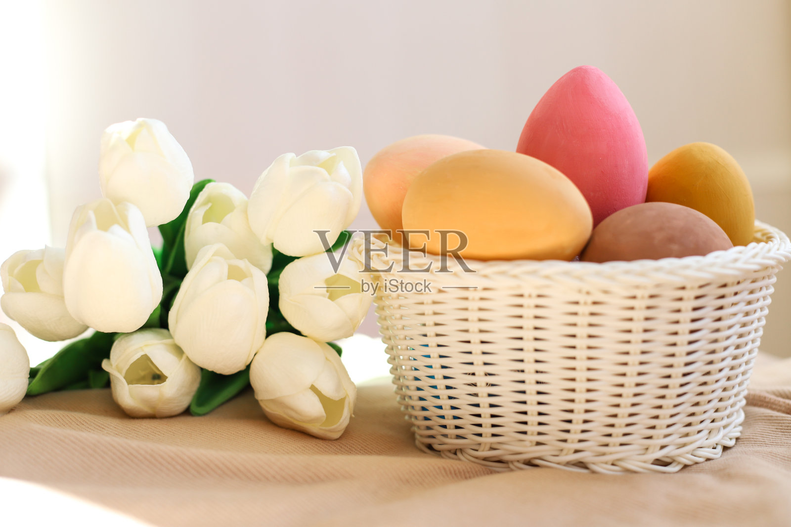这是一个彩色复活节彩蛋篮子的特写，背景是白色的郁金香。节日和复活节的概念照片摄影图片