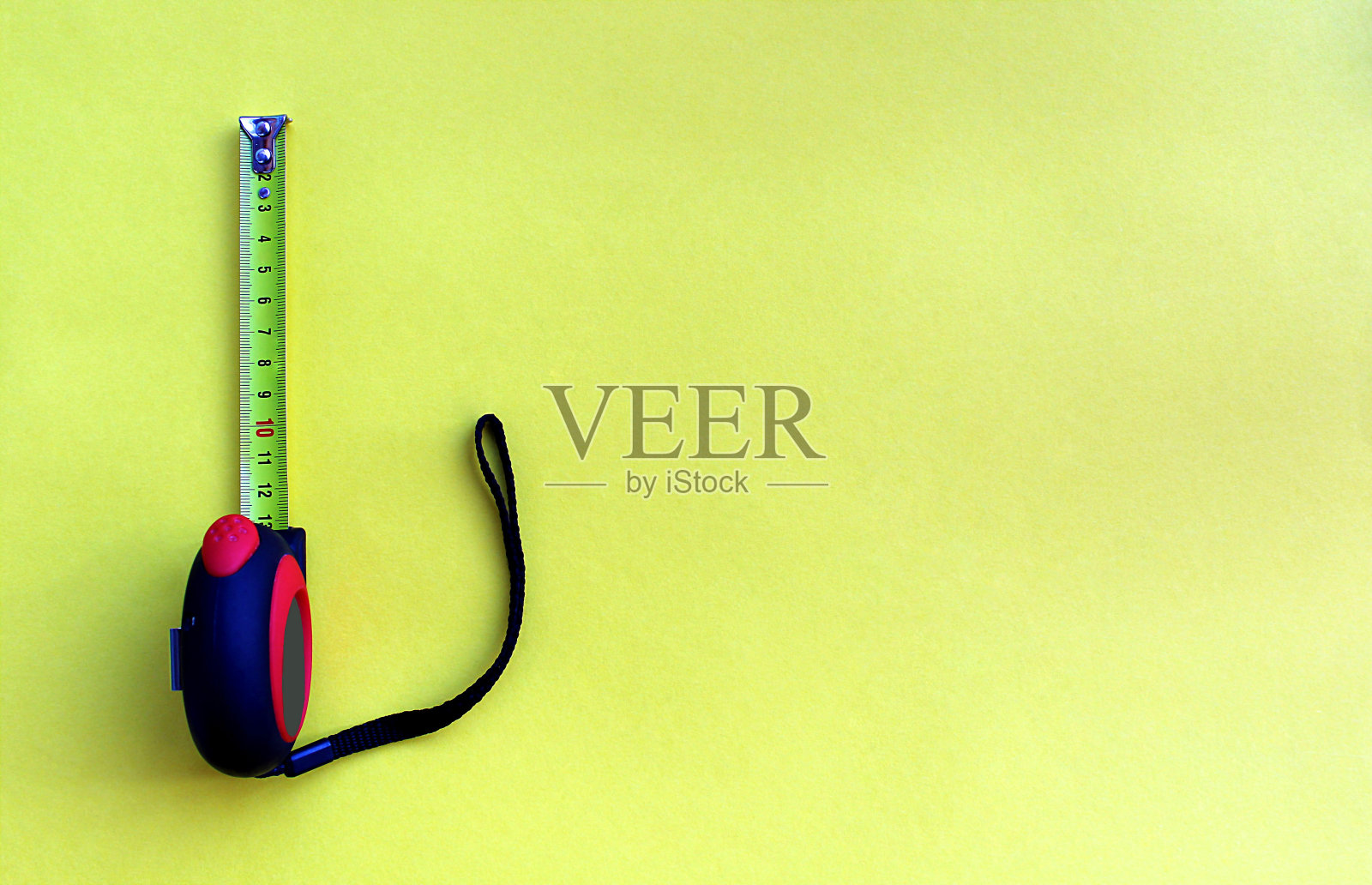 一个建筑卷尺放在黄色的背景上，上面有一个地方是用来写文字的。照片摄影图片