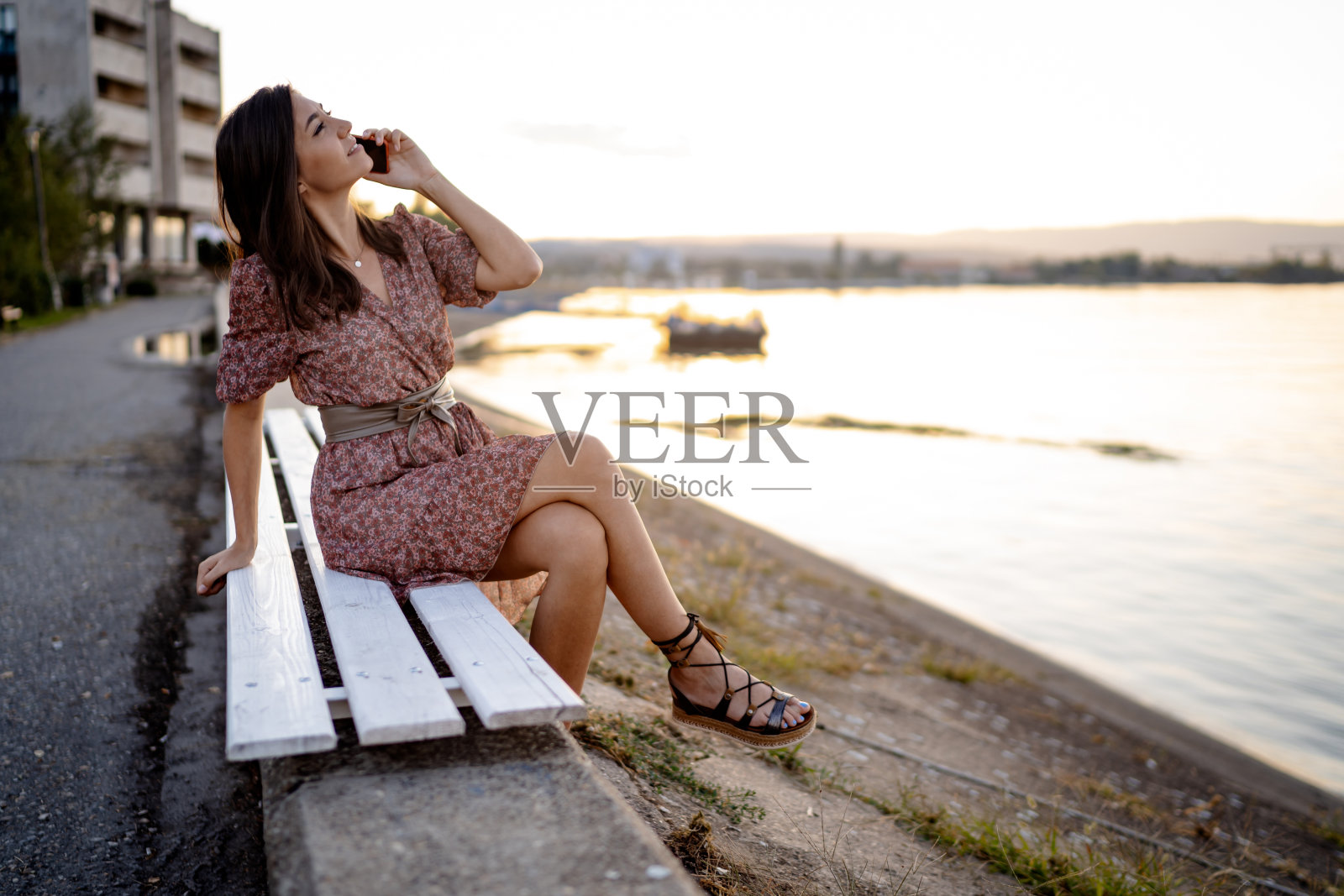 年轻女子坐在沙滩上的长椅上用智能手机聊天照片摄影图片