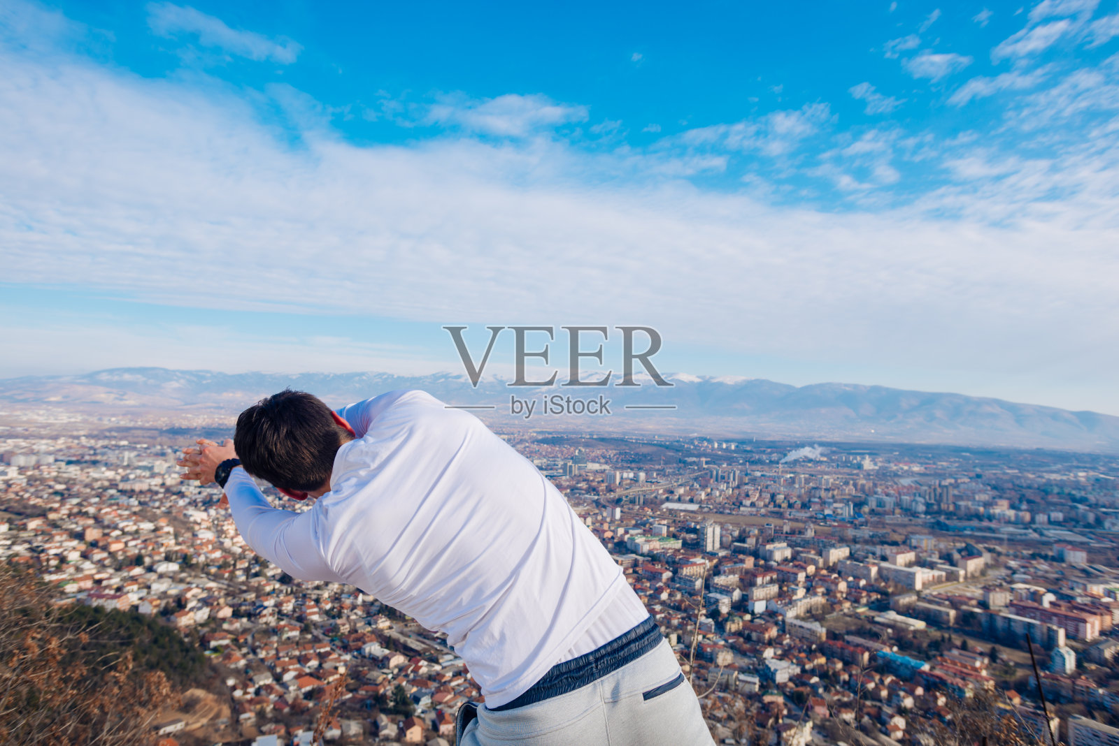 一个年轻强壮的男子在早上一边看城市一边锻炼。照片摄影图片