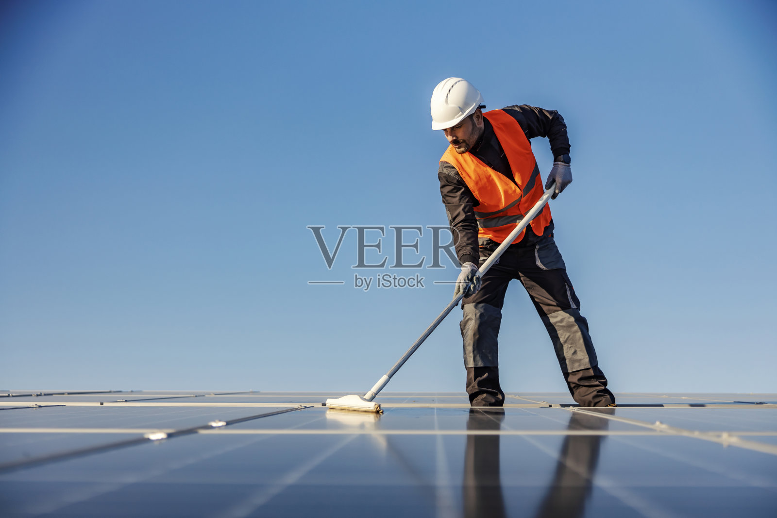 一名工人在维护屋顶上的太阳能电池板。照片摄影图片