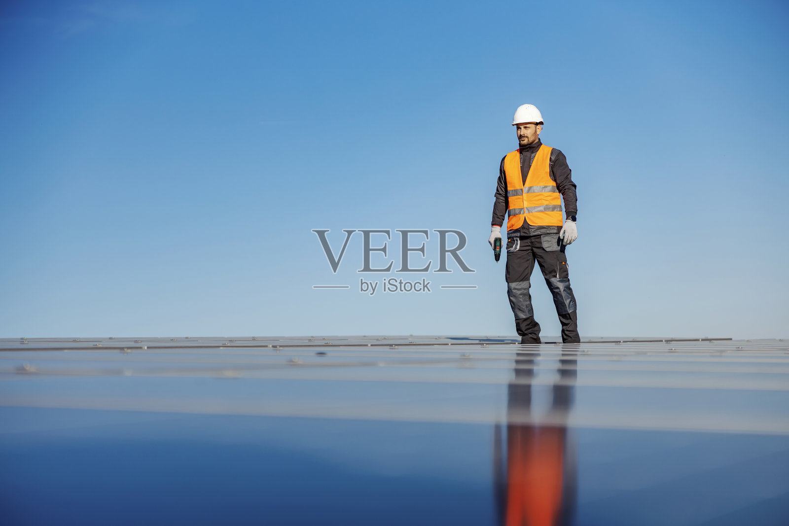 准备安装太阳能电池板的工人，手里拿着螺丝刀。照片摄影图片