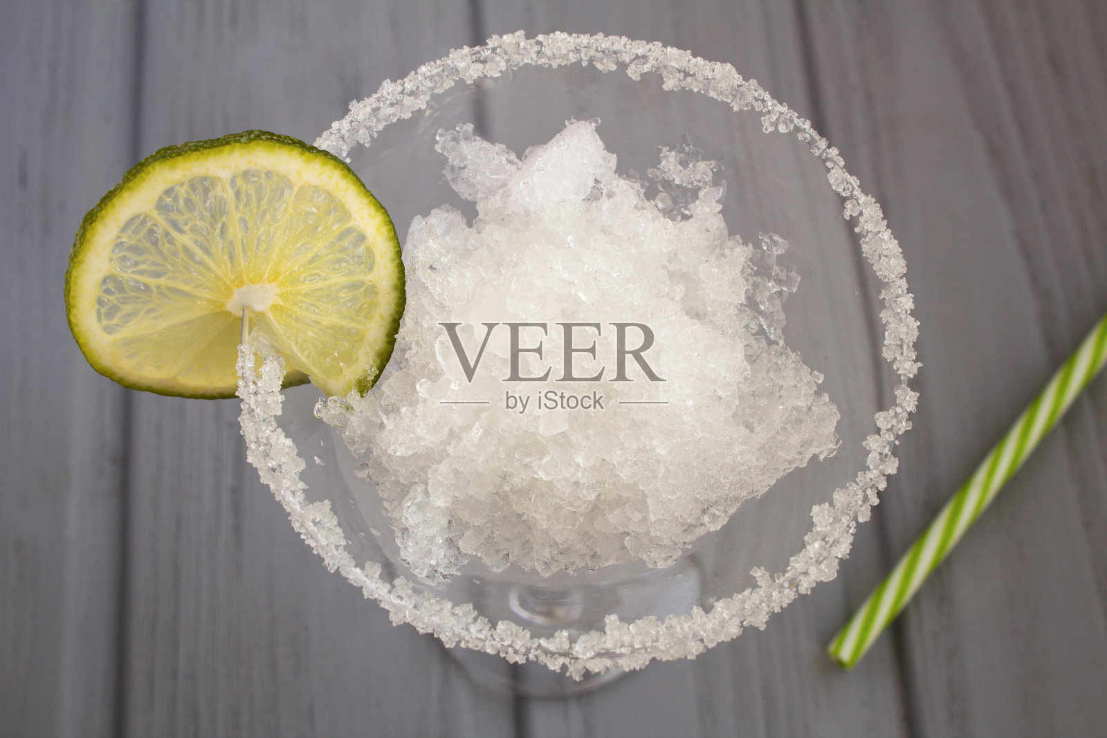 冰冻的果汁和酸橙在灰色木质背景的葡萄酒杯里。特写镜头。照片摄影图片