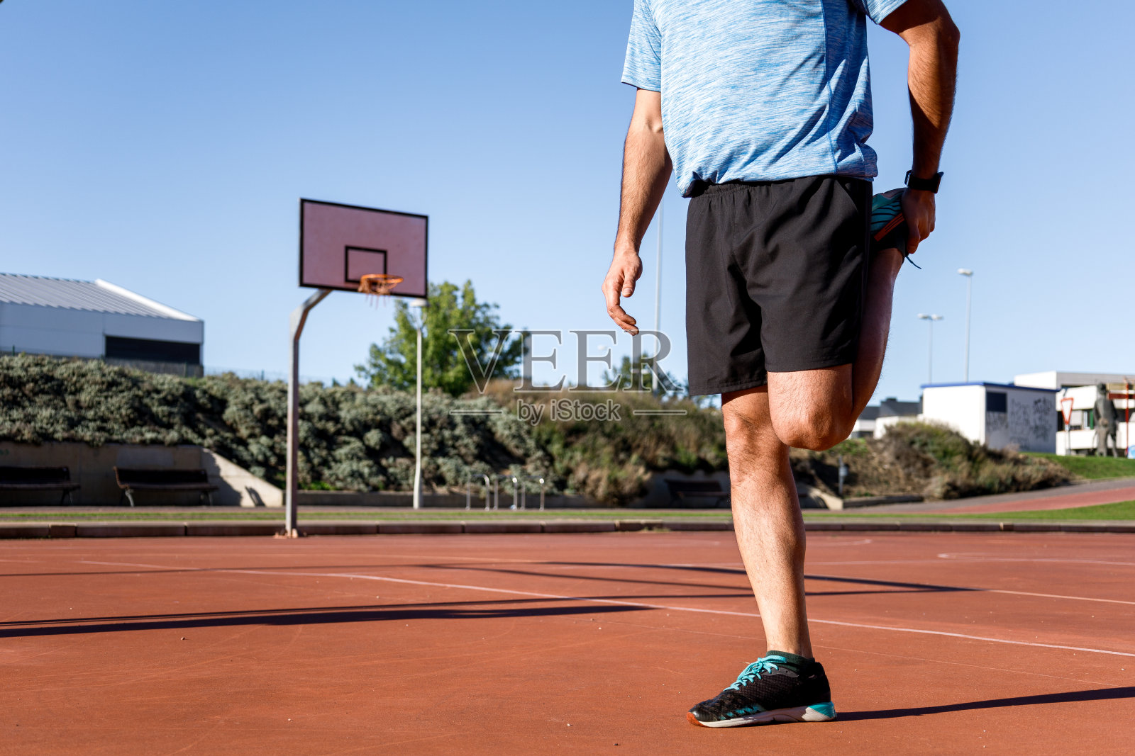 一个无法辨认的白人男子在打篮球前在户外伸展四头肌照片摄影图片