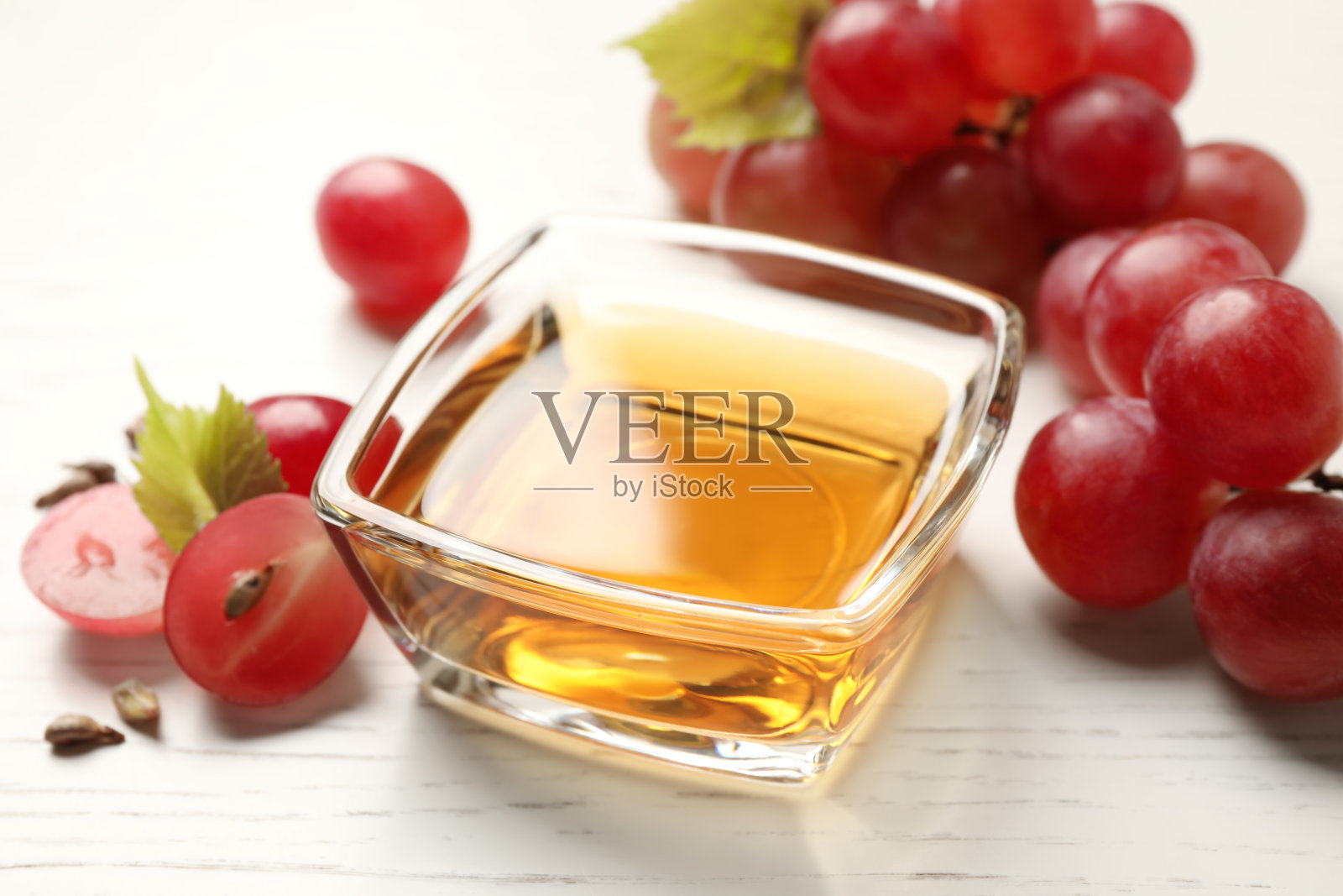 玻璃碗天然葡萄籽油在白色木桌上。有机化妆品照片摄影图片