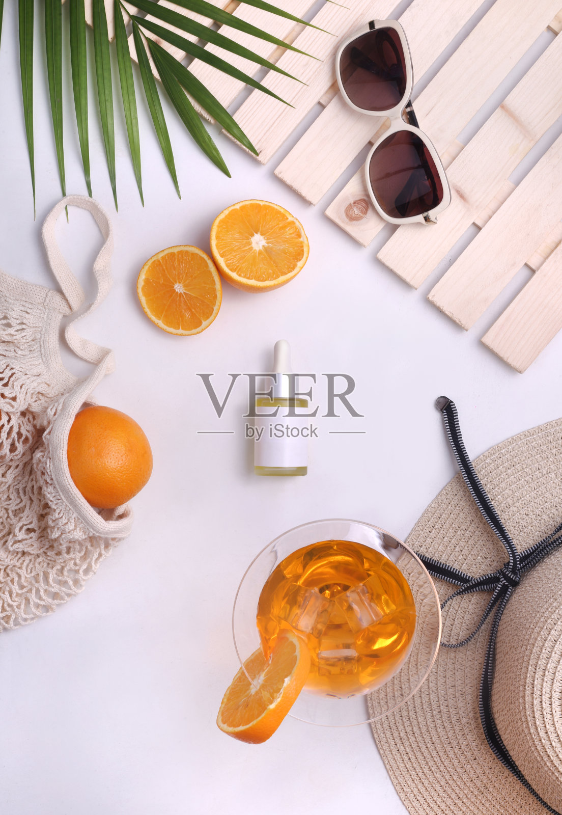 用帽子、橘子、棕榈叶、果汁等夏季道具平铺维生素c护肤产品。俯视图照片摄影图片
