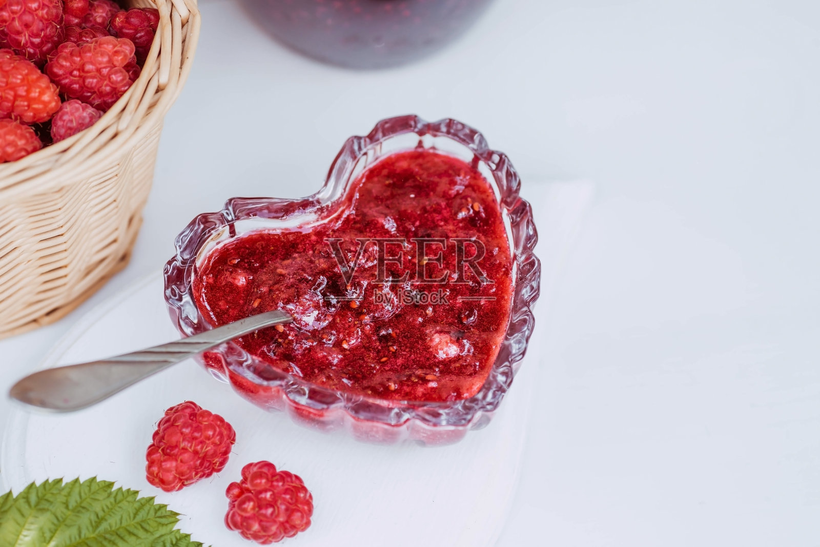 白色木桌上自制健康果酱配树莓。治疗感冒。养护和夏季收获。照片摄影图片