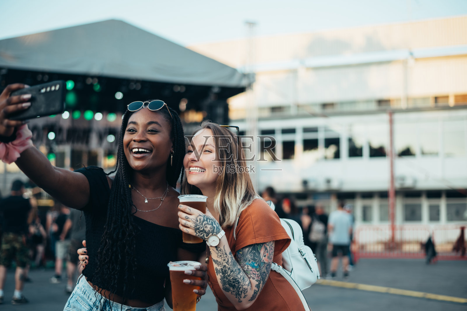 两个漂亮的朋友在音乐节上用智能手机自拍照片摄影图片