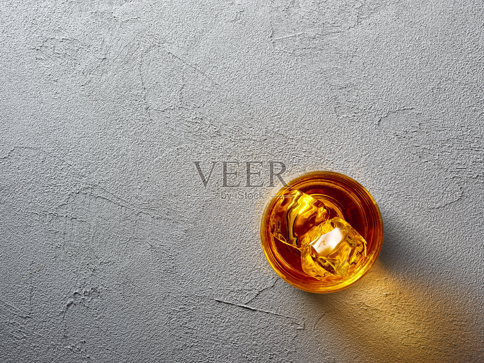 一杯优雅的威士忌加冰在灰色纹理的柜台上。照片摄影图片