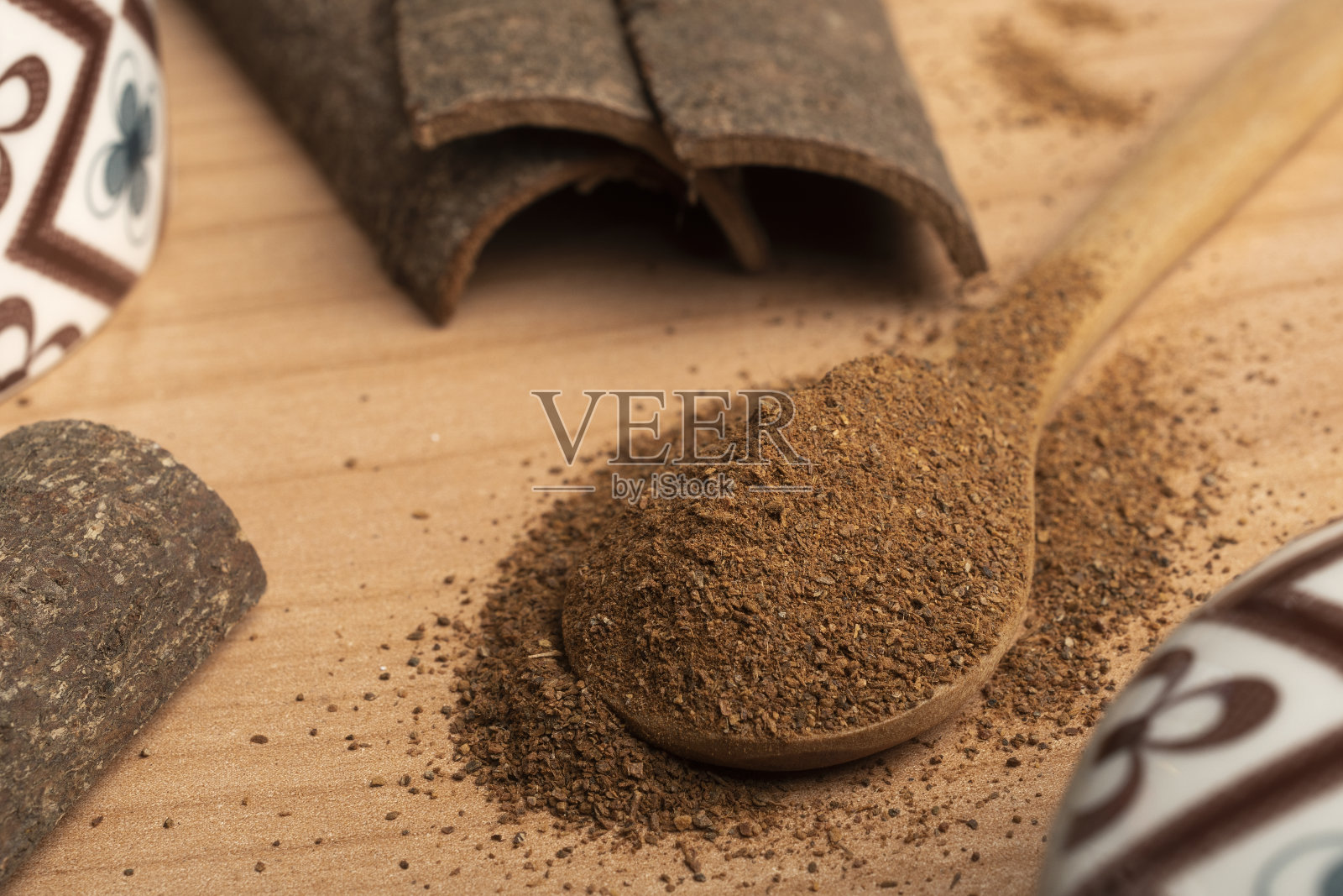 木勺装满肉桂粉，放在桌子上，配上一些肉桂棒照片摄影图片