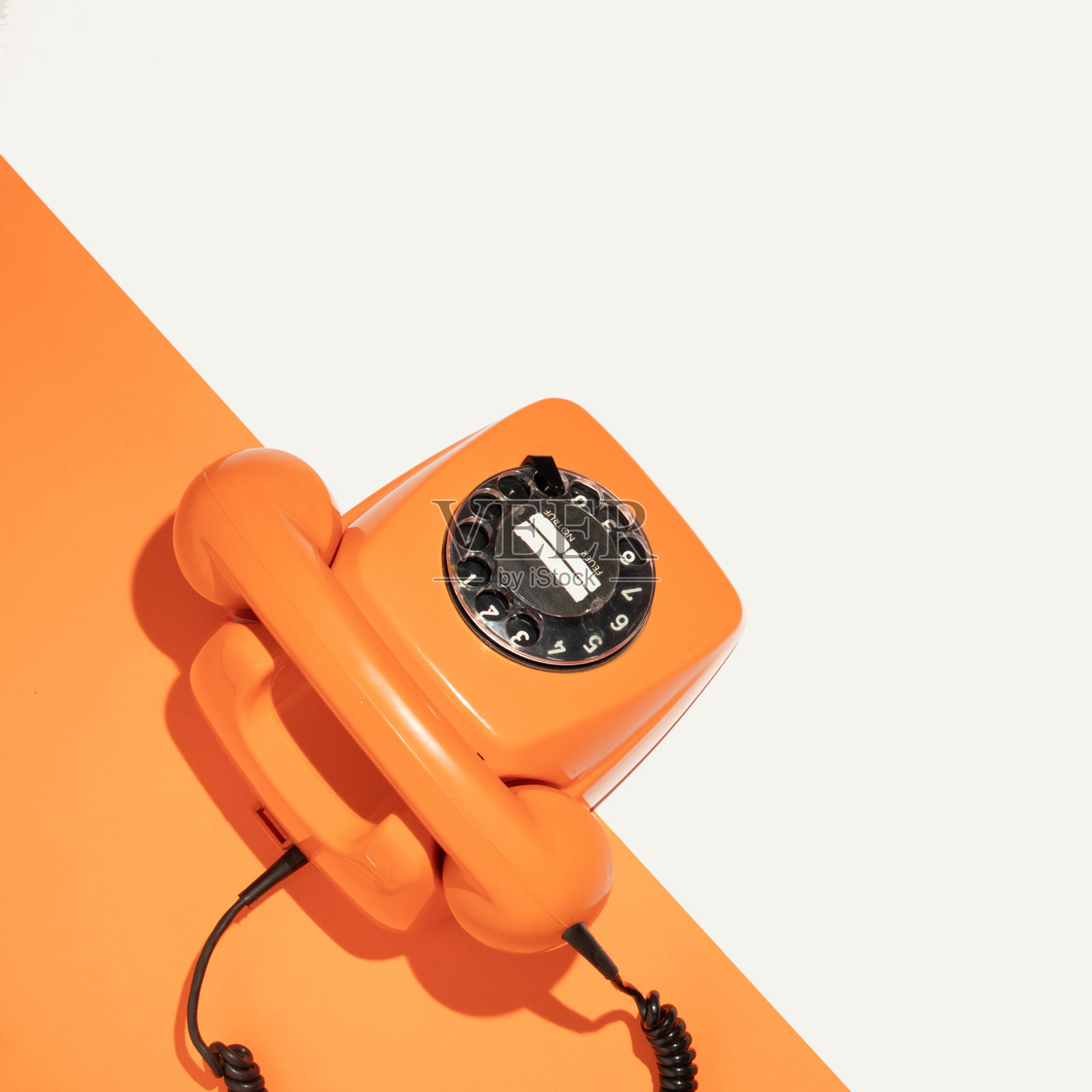 创意布局与复古橙色手机在白色和明亮的橙色背景。幸福的生活理念与古老的电话。春季或夏季最小的时尚组合与手集。平的。照片摄影图片