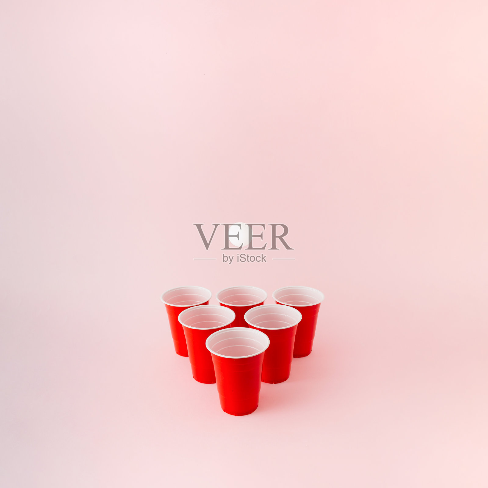 六个红色塑料啤酒桌球杯，白色的球在上面盘旋。照片摄影图片