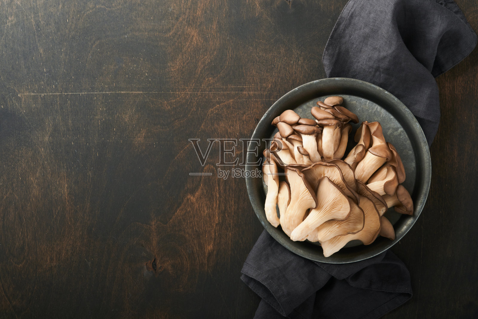 新鲜牡蛎蘑菇。铁旧碗美味的有机牡蛎蘑菇在旧木制背景，顶部视图与文字空间。照片摄影图片