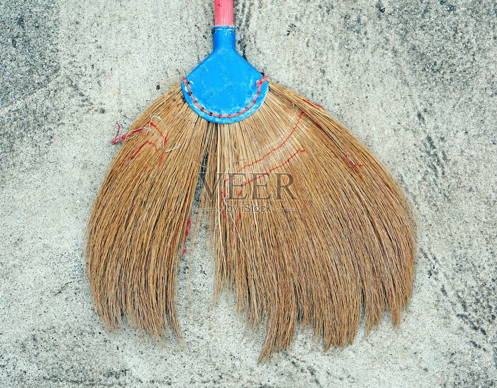 水泥地上有一把坏掉的泰国扫帚。照片摄影图片