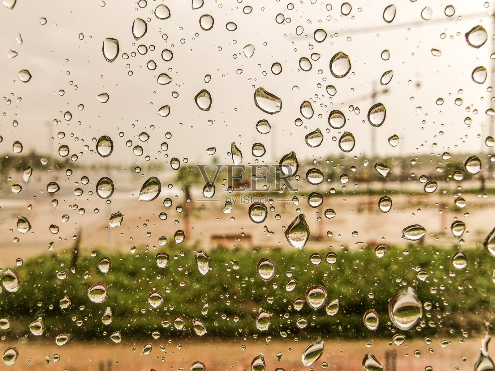 雨点在暴风雨后落在窗户上，背景是公园里的散焦长椅照片摄影图片