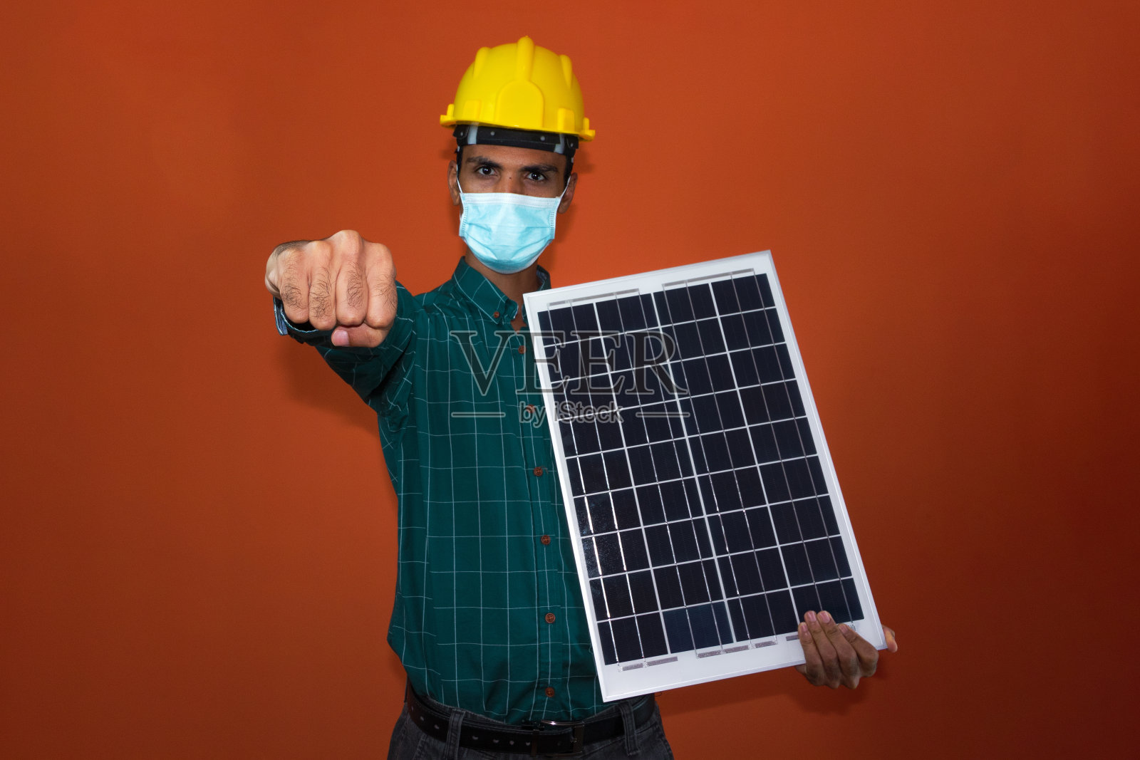 戴着头盔和口罩的工人拿着太阳能光伏板隔离。照片摄影图片