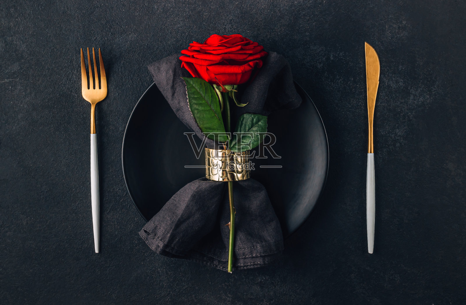 情人节的节日餐桌上摆放着餐具、玫瑰和心形巧克力。平躺照片摄影图片