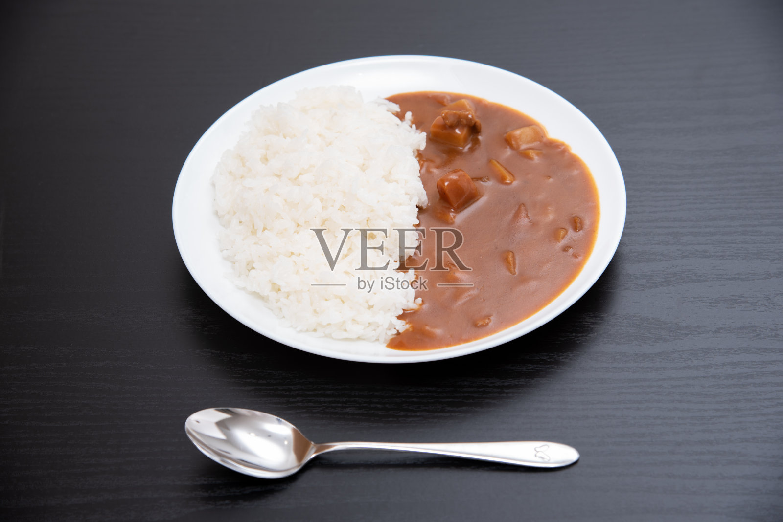 用黑色背景的圆形盘子盛着咖喱米饭照片摄影图片