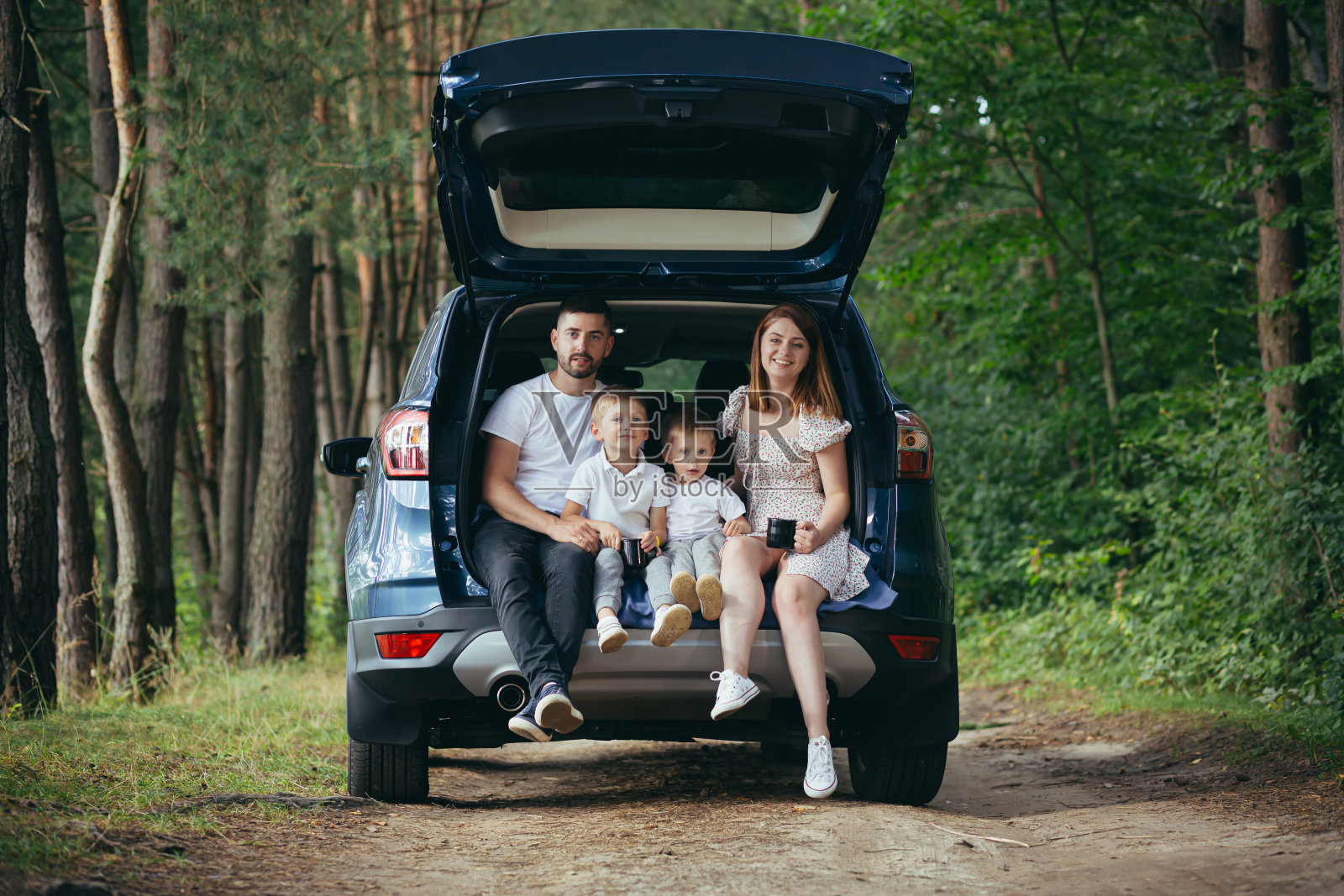 快乐的年轻家庭一起旅行度假。父母爸爸妈妈带着可爱的孩子坐在汽车后备箱附近露营，在森林远足之前有野餐休息放松的下次旅行照片摄影图片