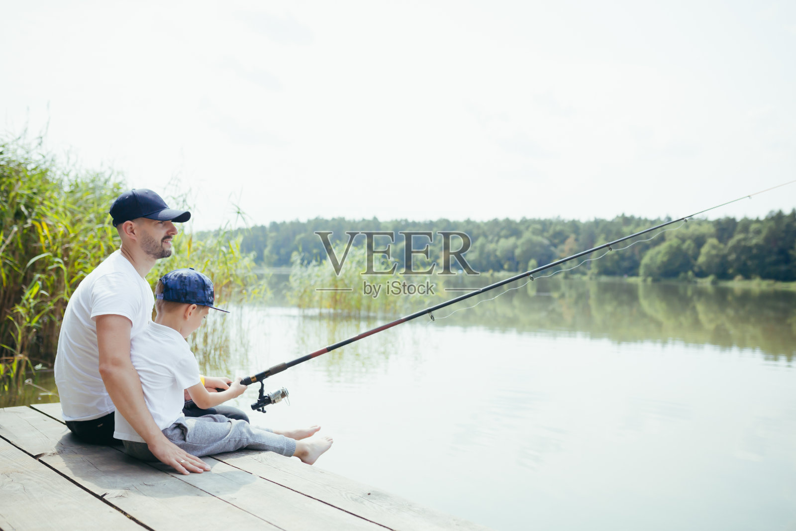 父亲和儿子在湖上钓鱼，丈夫和孩子一起野餐照片摄影图片