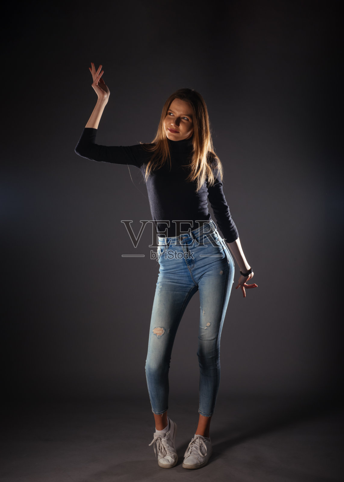 迷人的女模特在牛仔布牛仔裤摆孤立的灰色背景。照片摄影图片