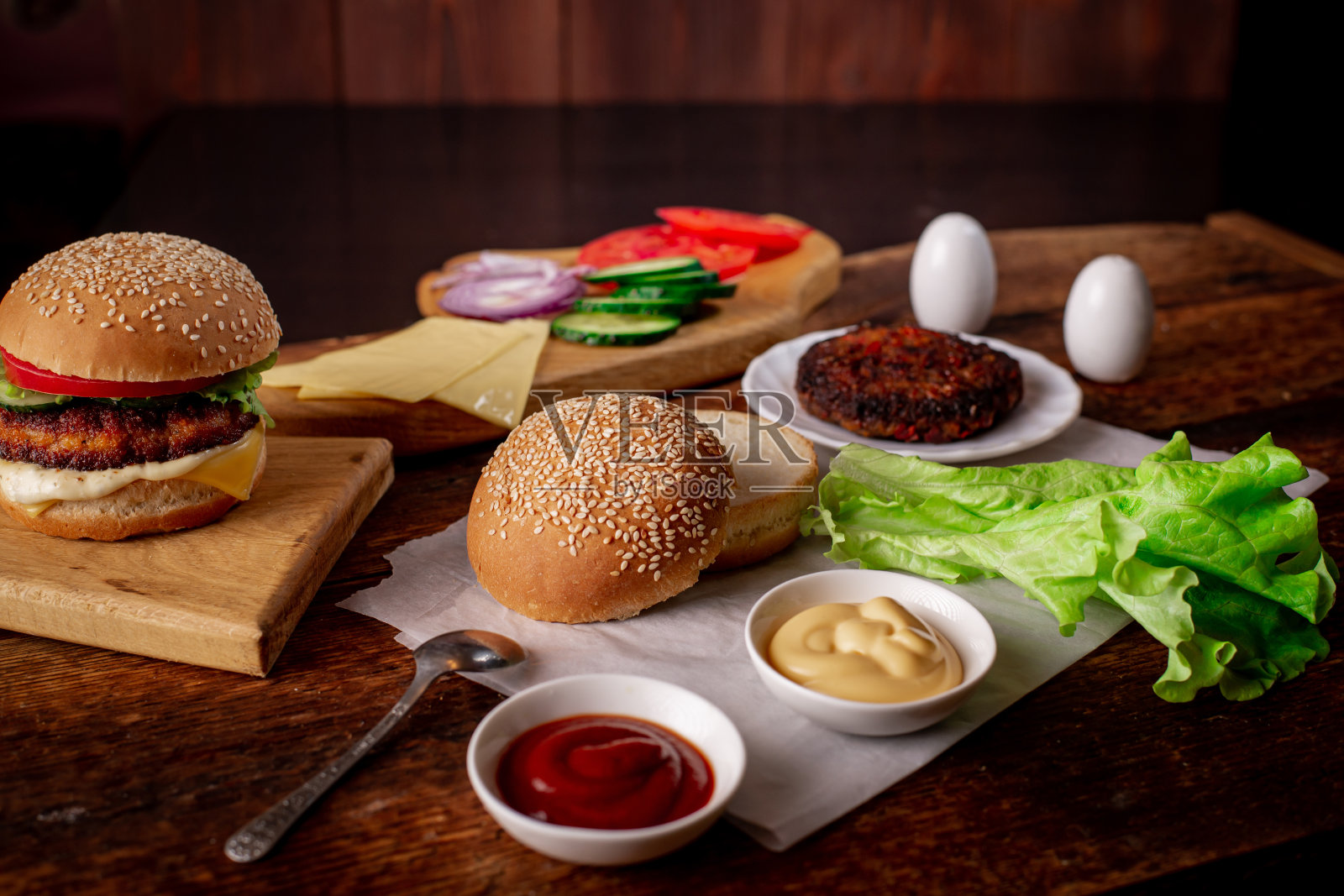 汉堡的一天。做汉堡或芝士汉堡。经典汉堡的不同配料。文本。木制背景。照片摄影图片