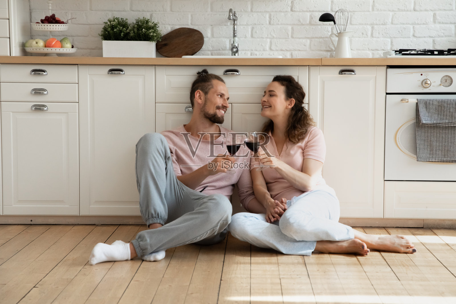 快乐甜蜜的年轻夫妇坐在厨房的地板上照片摄影图片