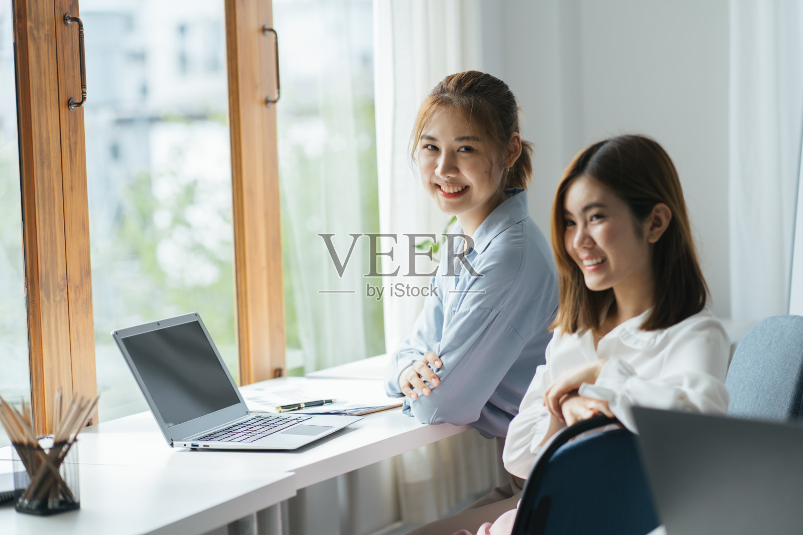 两个亚洲同事一起工作，在办公室用笔记本电脑讨论财务文件照片摄影图片