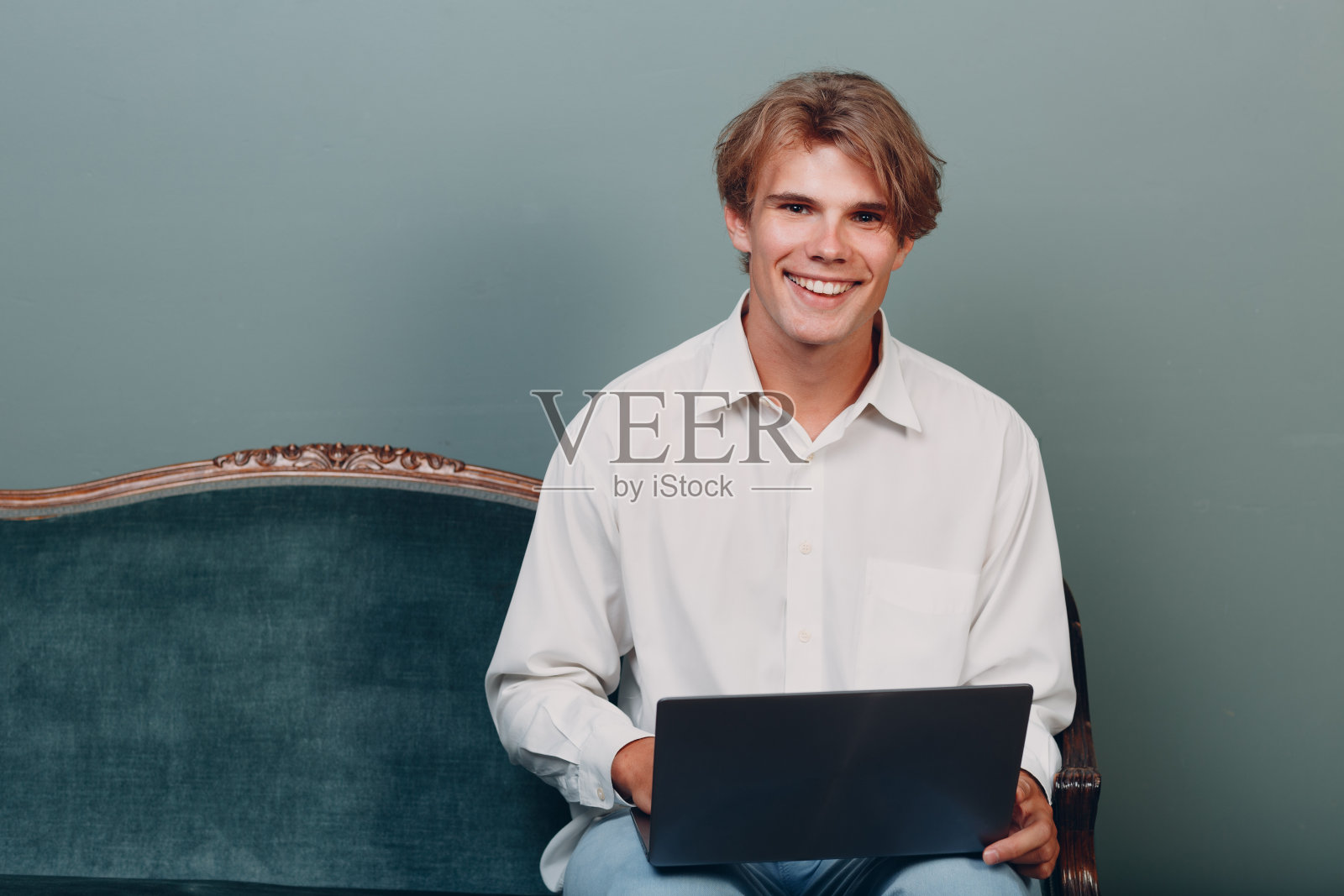 肖像年轻男子坐在笔记本电脑在工作室。照片摄影图片