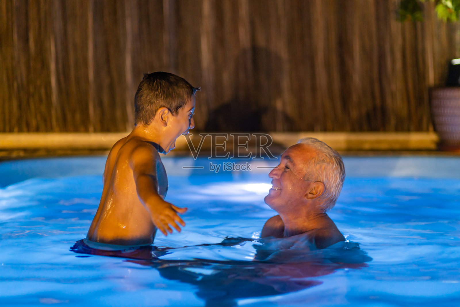 晚上爷爷和孙子在游泳池里玩耍照片摄影图片