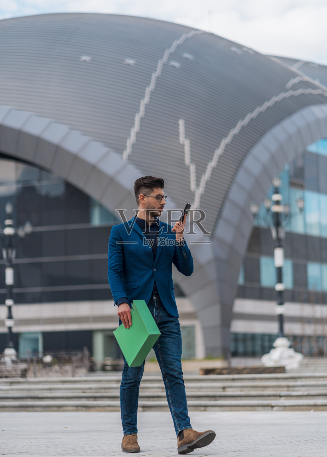 穿着蓝色西装的时尚商人看着他的智能手机照片摄影图片