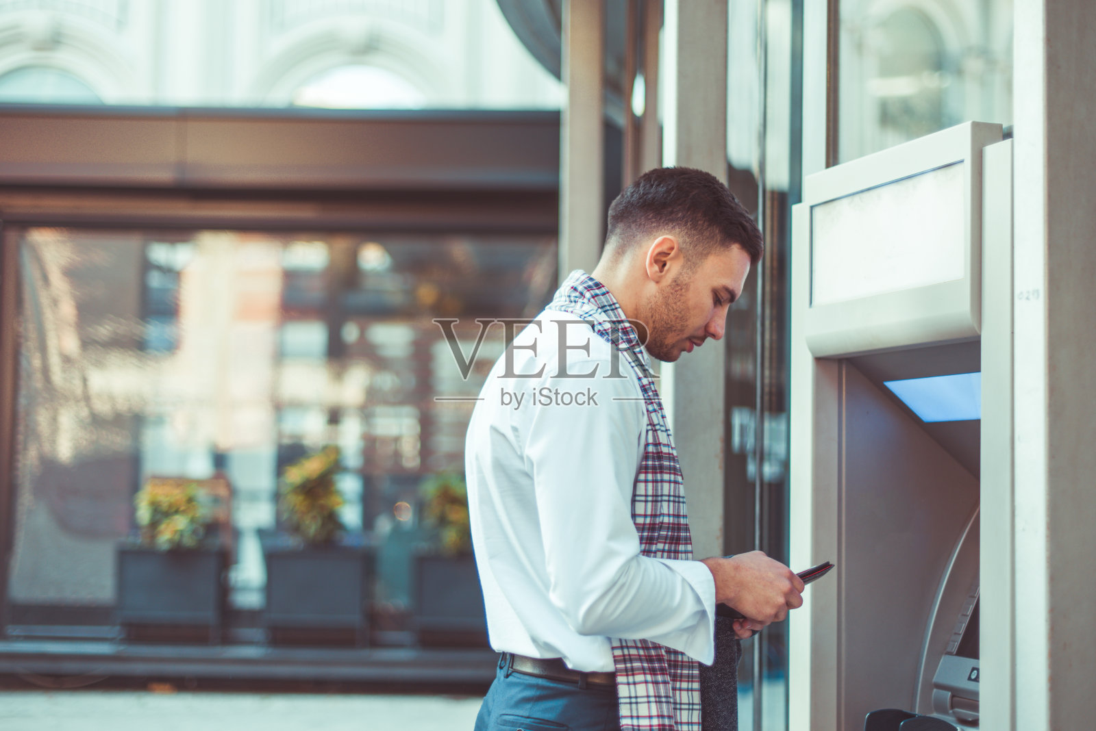 站在自动取款机旁的英俊商人照片摄影图片