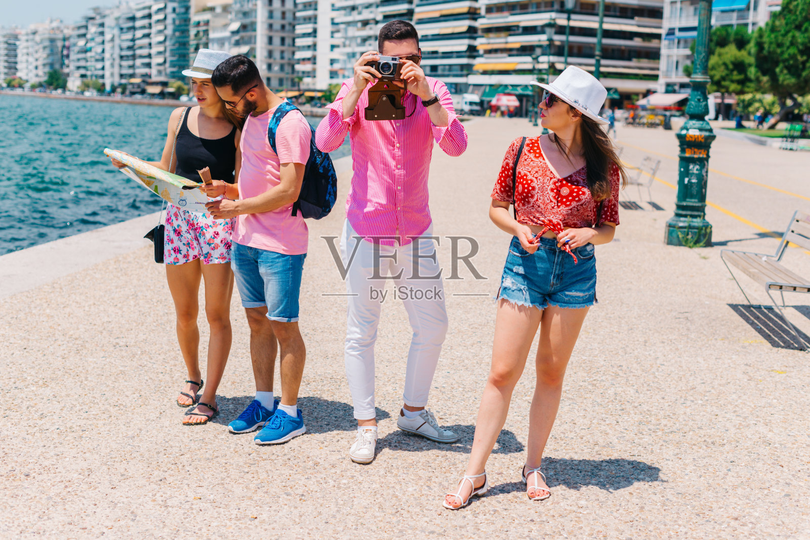 一对夫妇正在看地图，而另一对夫妇正在他们的暑假里拍照。照片摄影图片