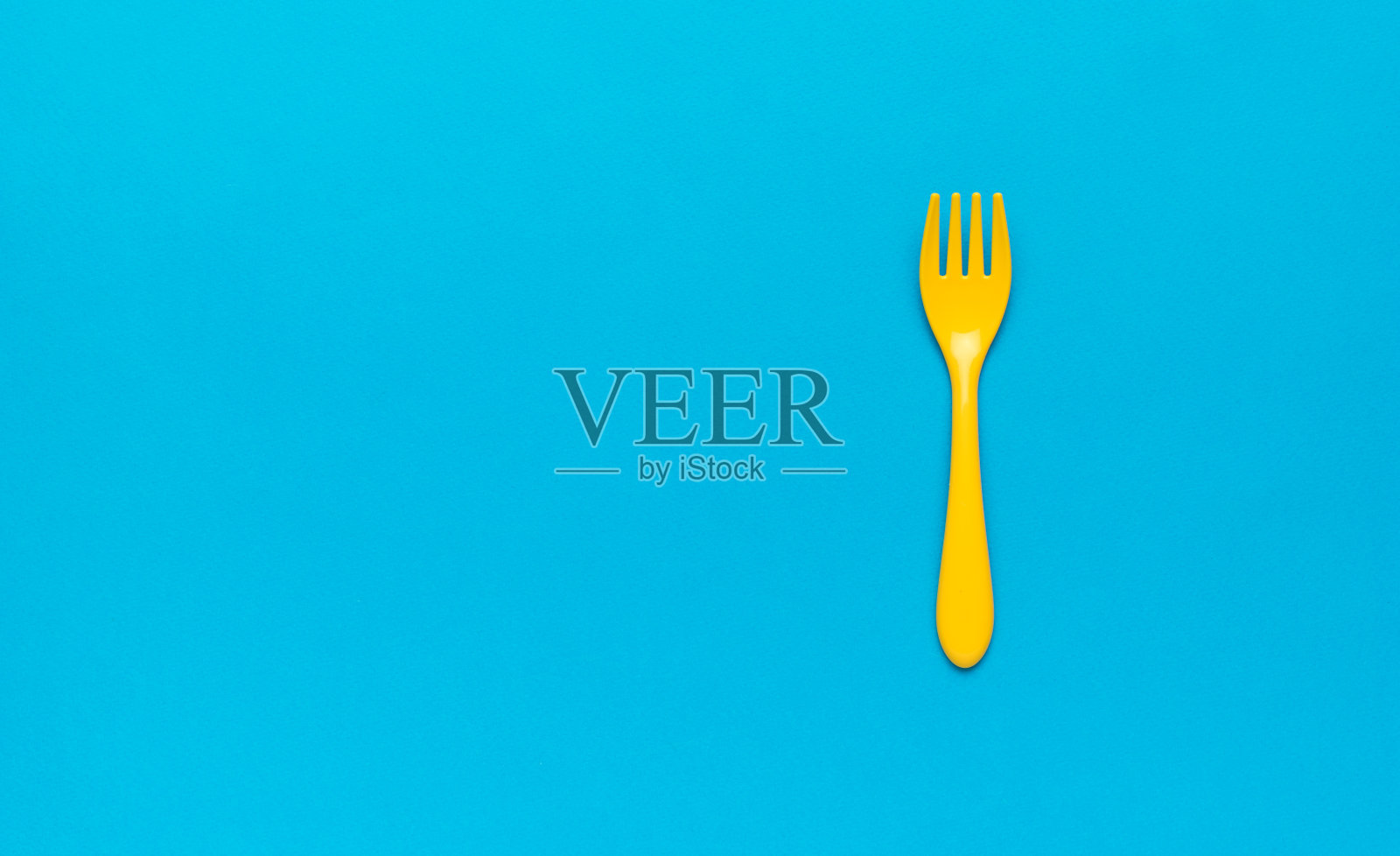 美丽的塑料黄色叉子在蓝色的背景。空间的文本。平的。照片摄影图片