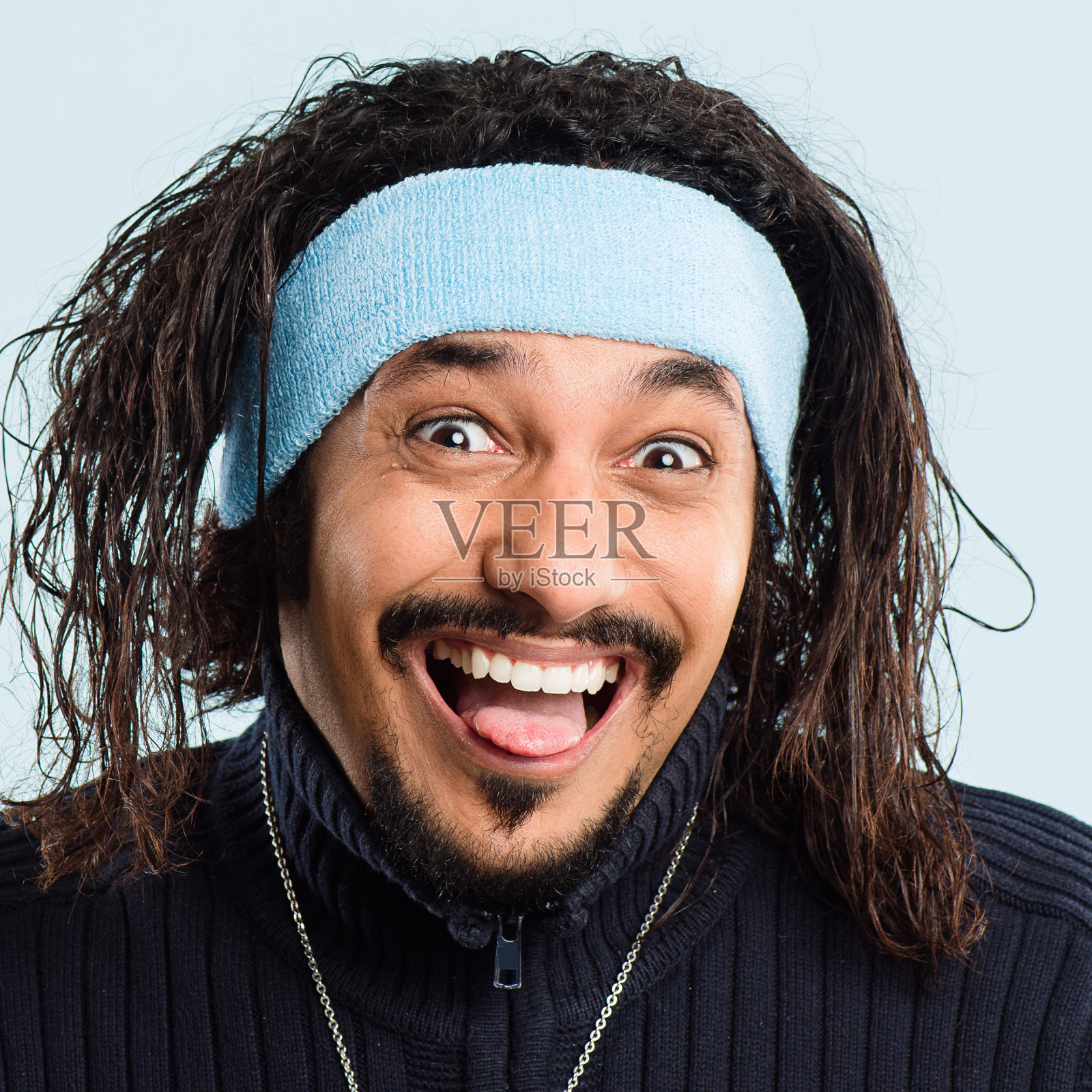 一个英俊的年轻人独自站在演播室里，做着鬼脸照片摄影图片